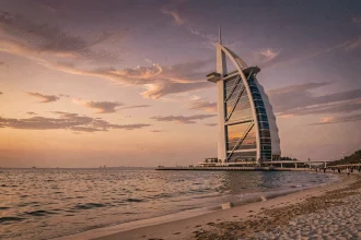 Vue panoramique du Burj Al Arab depuis la plage de Jumeirah au coucher du soleil, reflété dans les eaux du golfe Persique