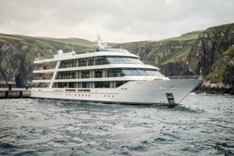 Navire de croisière Uhaina naviguant le long de la côte atlantique rocheuse sous un ciel dégagé